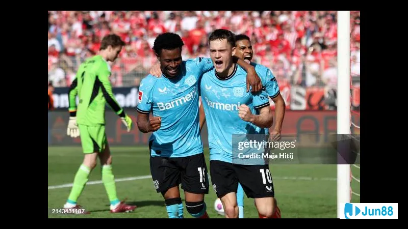 Cầu thủ Bayer Leverkusen dùng kỹ thuật đi bóng qua hậu vệ Union Berlin trên sân cỏ